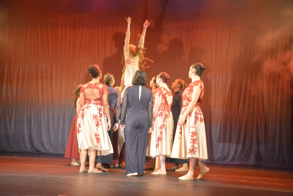 Bailarinas em roda, de mãos estendidas para uma colega erguida ao centro, no espetáculo Travessia, em 2026.